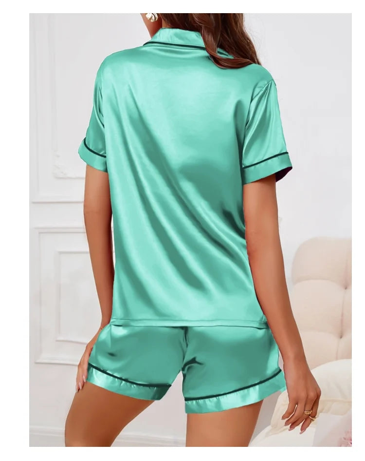 Pyjama femme vert en satin, manches courtes et short, col type chemise avec petite poche à gauche, liseré noir sur les côtés, confortable et élégant pour l’été ou les soirées cocooning.