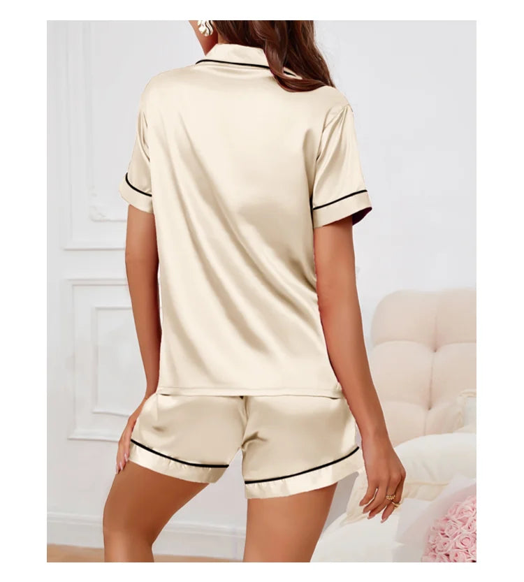 Pyjama femme ivoire en satin, manches courtes et short, col type chemise avec petite poche à gauche, liseré noir sur les côtés, confortable et élégant pour l’été ou les soirées cocooning.